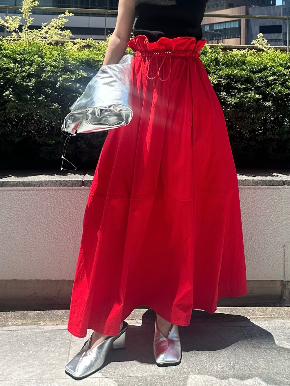 レッド系のスカート、シルバー系のパンプス、シルバー系のトートバッグを着用したレディースの夏コーディネートの9枚目の写真