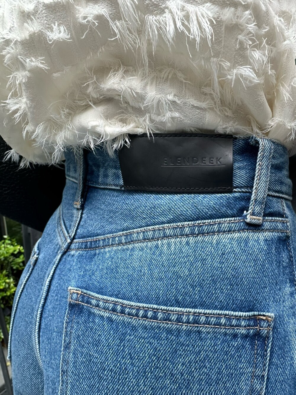 ブルー系のデニムパンツ、ホワイト系のキャミソール、ホワイト系のニット/セーターを着用したレディースの冬コーディネートの4枚目の写真