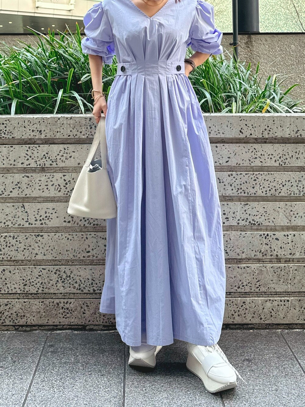 ホワイト系のハンドバッグ、ホワイト系のスニーカー、ブルー系のワンピースを着用したレディースの冬コーディネートの2枚目の写真