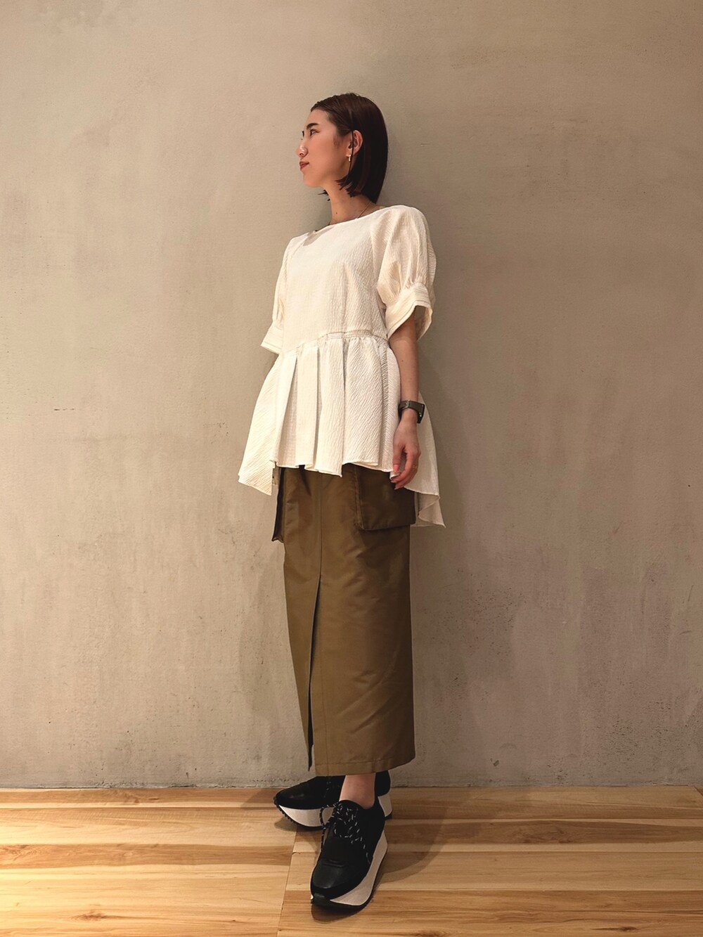 ブラウン系のスカート、ブラック系のスニーカー、ホワイト系のシャツ/ブラウスを着用したレディースの春コーディネートの3枚目の写真