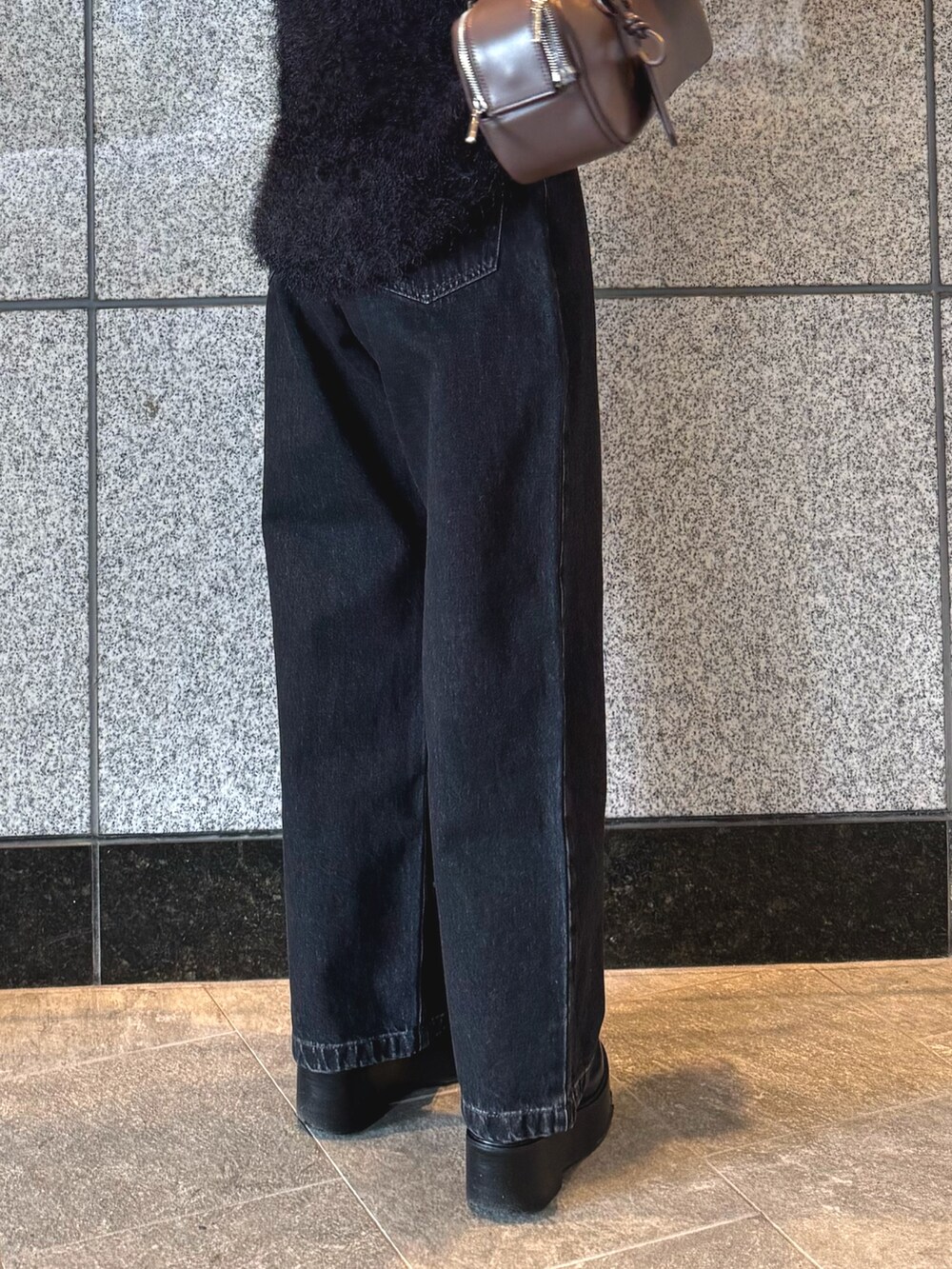 ブラック系のニット/セーター、ブラック系のデニムパンツ、ブラウン系のボストンバッグを着用したレディースの冬コーディネートの9枚目の写真