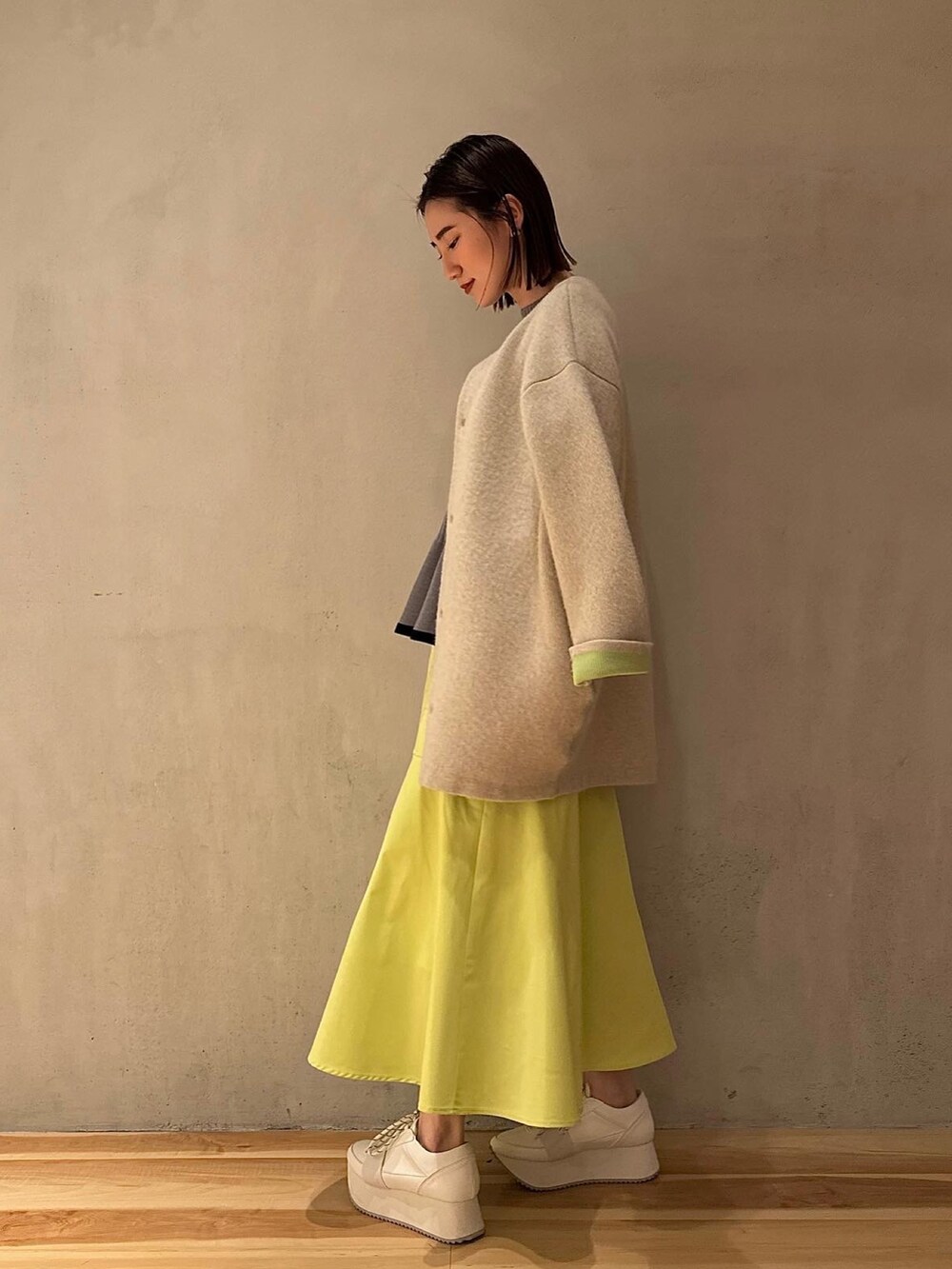 グレー系のニット/セーター、イエロー系のスカート、ホワイト系のスニーカーを着用したレディースの冬コーディネートの8枚目の写真