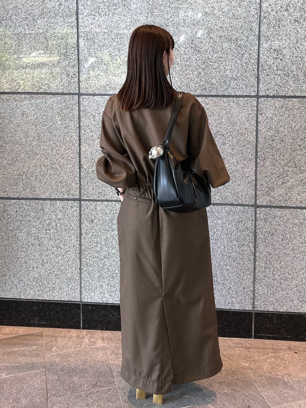 ブラウン系のワンピース、ゴールド系のブーツ、ブラック系のハンドバッグを着用したレディースの秋コーディネートの5枚目の写真