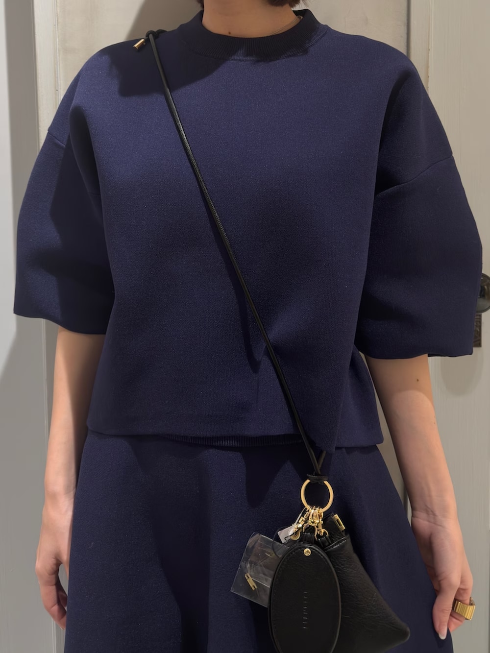 ブルー系のニット/セーター、ブルー系のスカート、ブラック系のスマホグッズを着用したレディースの春コーディネートの6枚目の写真