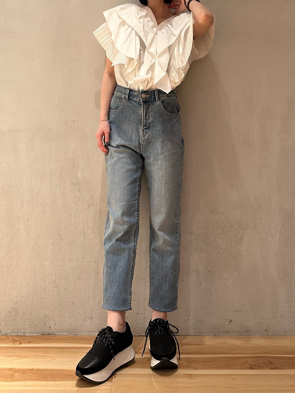 ホワイト系のシャツ/ブラウス、ブラック系のスニーカー、ブルー系のデニムパンツを着用したレディースの春コーディネートの2枚目の写真