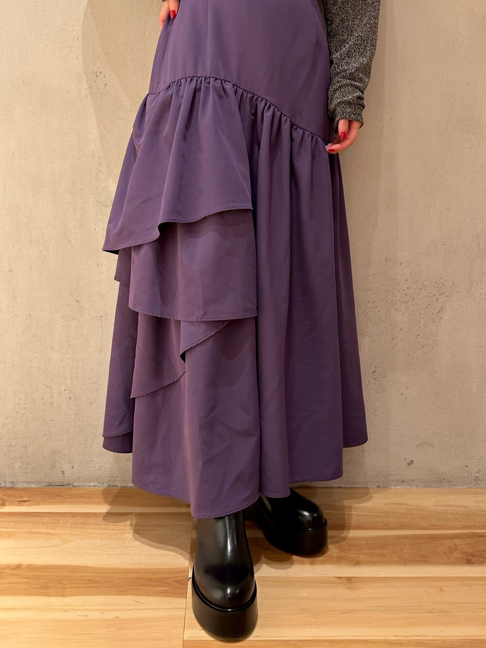 パープル系のスカート、ブラック系のノーカラーコート、シルバー系のTシャツ/カットソーを着用したレディースの秋コーディネートの7枚目の写真