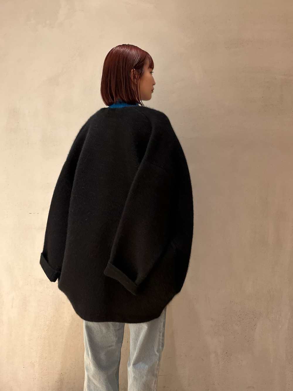 ブラック系のノーカラージャケット、ブルー系のニット/セーター、ブルー系のデニムパンツを着用したレディースの夏コーディネートの6枚目の写真