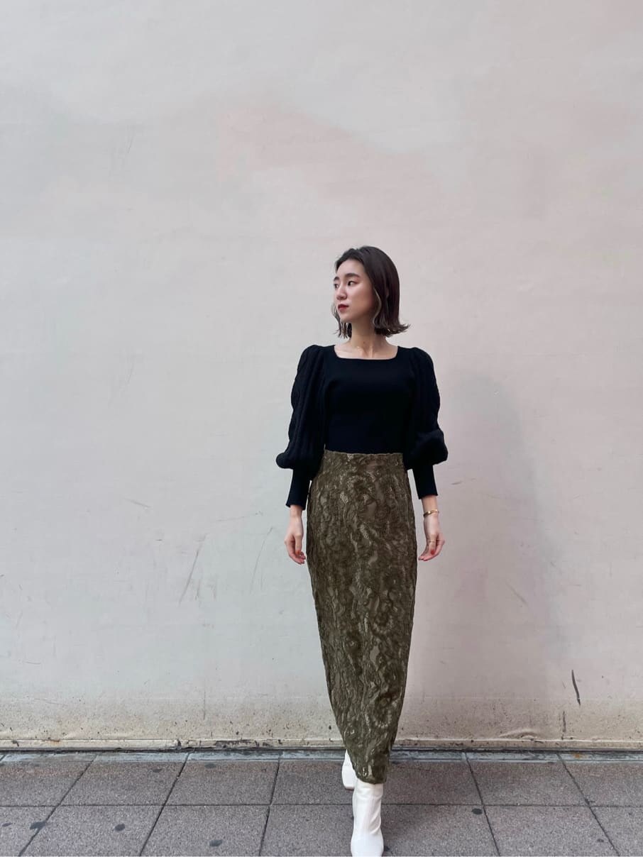 ホワイト系のその他シューズ、ベージュ系のその他アウター、ブラック系のニット/セーターを着用したレディースの冬コーディネートの2枚目の写真