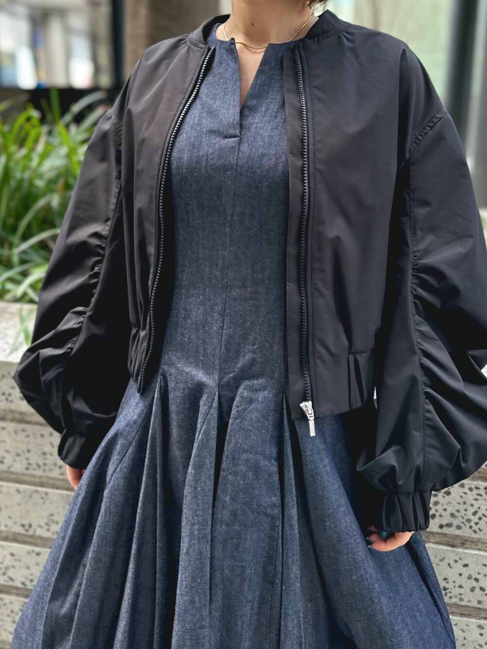 ホワイト系のスニーカー、ブルー系のワンピース、ブラック系のブルゾンを着用したレディースの春コーディネートの2枚目の写真