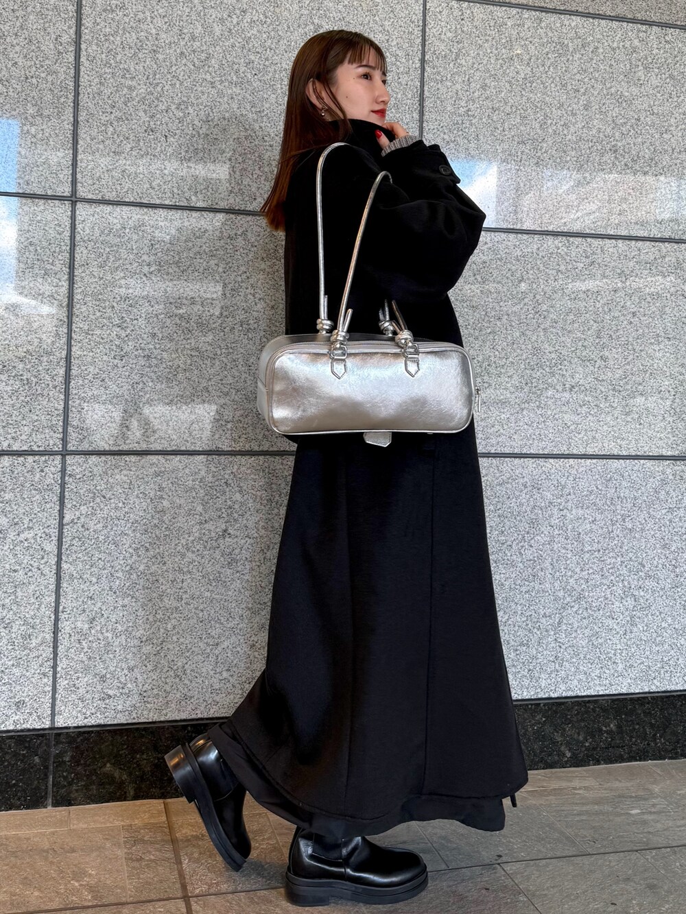 ブラック系のその他アウター、シルバー系のボストンバッグ、ブラック系のブーツを着用したレディースの冬コーディネートの3枚目の写真