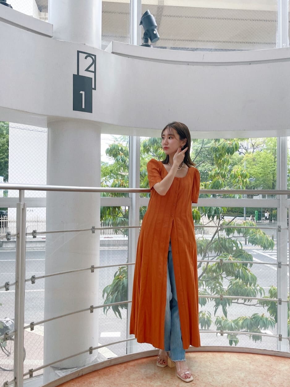 オレンジ系のワンピース、シルバー系のネックレスを着用したレディースの夏コーディネートの2枚目の写真