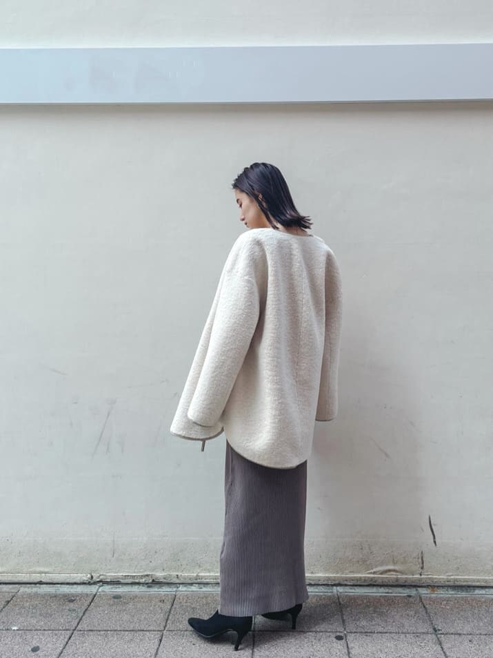 ブラック系のブーツ、ホワイト系のその他アウター、ベージュ系のワンピースを着用したレディースの秋コーディネートの7枚目の写真