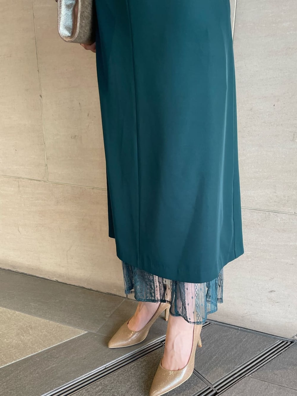 ゴールド系のパンプス、ゴールド系のクラッチバッグ、グリーン系のドレスを着用したレディースの夏コーディネートの4枚目の写真