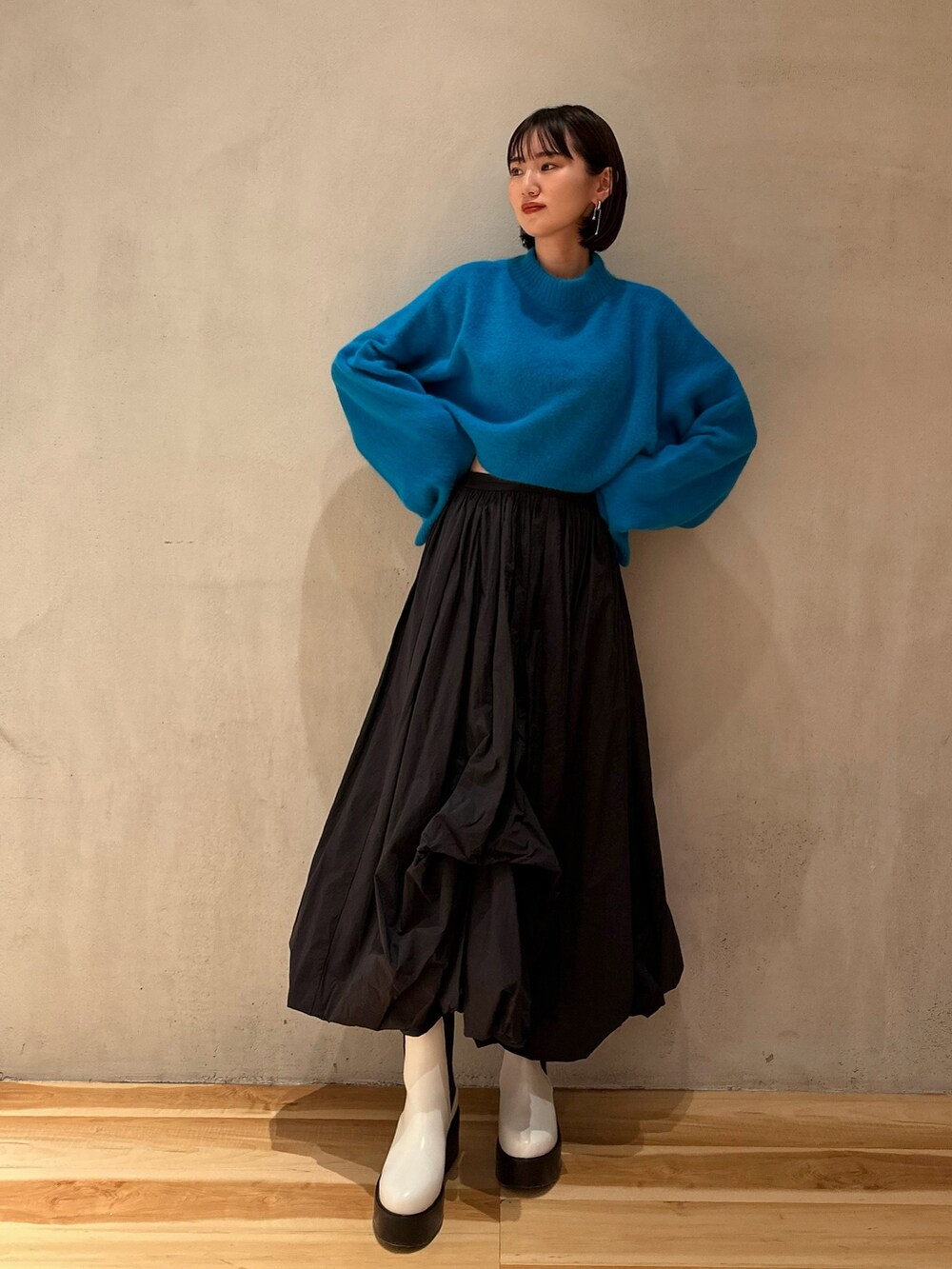 ブラック系のスカート、ブルー系のニット/セーター、ホワイト系のブーツを着用したレディースの冬コーディネートの2枚目の写真