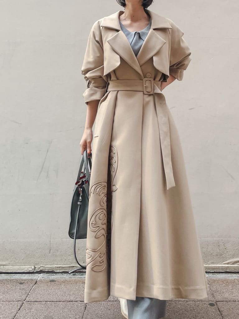 ベージュ系のトレンチコート、ブルー系のワンピース、ホワイト系のサンダルを着用したレディースの春コーディネートの2枚目の写真