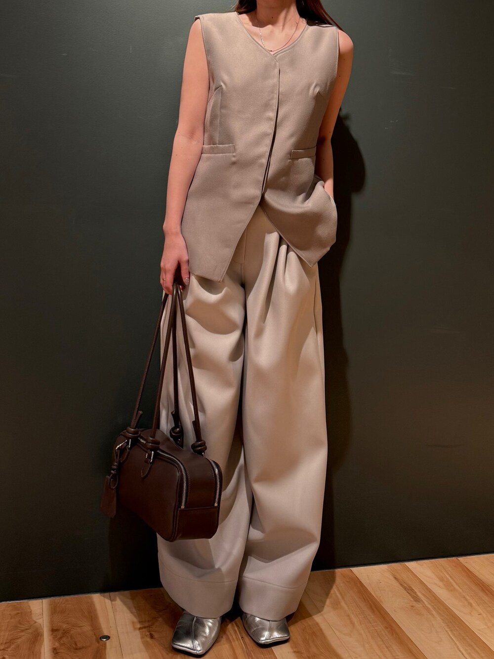 ベージュ系のベスト、ホワイト系のその他パンツ、ブラック系のボストンバッグを着用したレディースの冬コーディネートの2枚目の写真