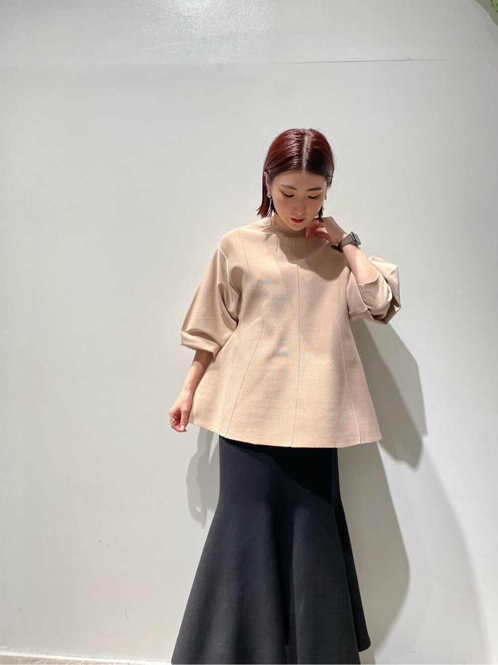 ブラウン系のノーカラーコート、ベージュ系のニット/セーター、ブラック系のブーツを着用したレディースの秋コーディネートの7枚目の写真