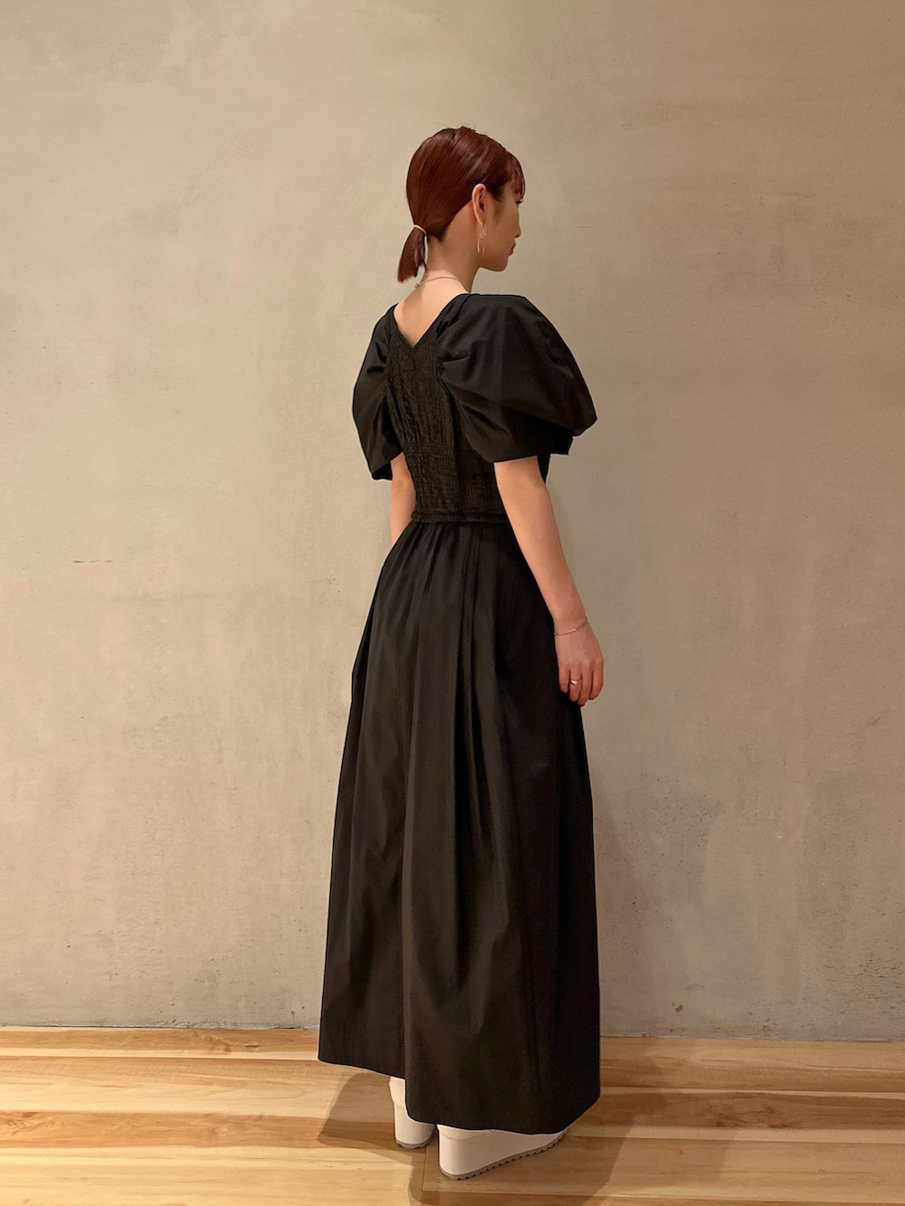 ブラック系のワンピース、ホワイト系のスニーカー、ゴールド系のピアス（両耳用）を着用したレディースの夏コーディネートの2枚目の写真