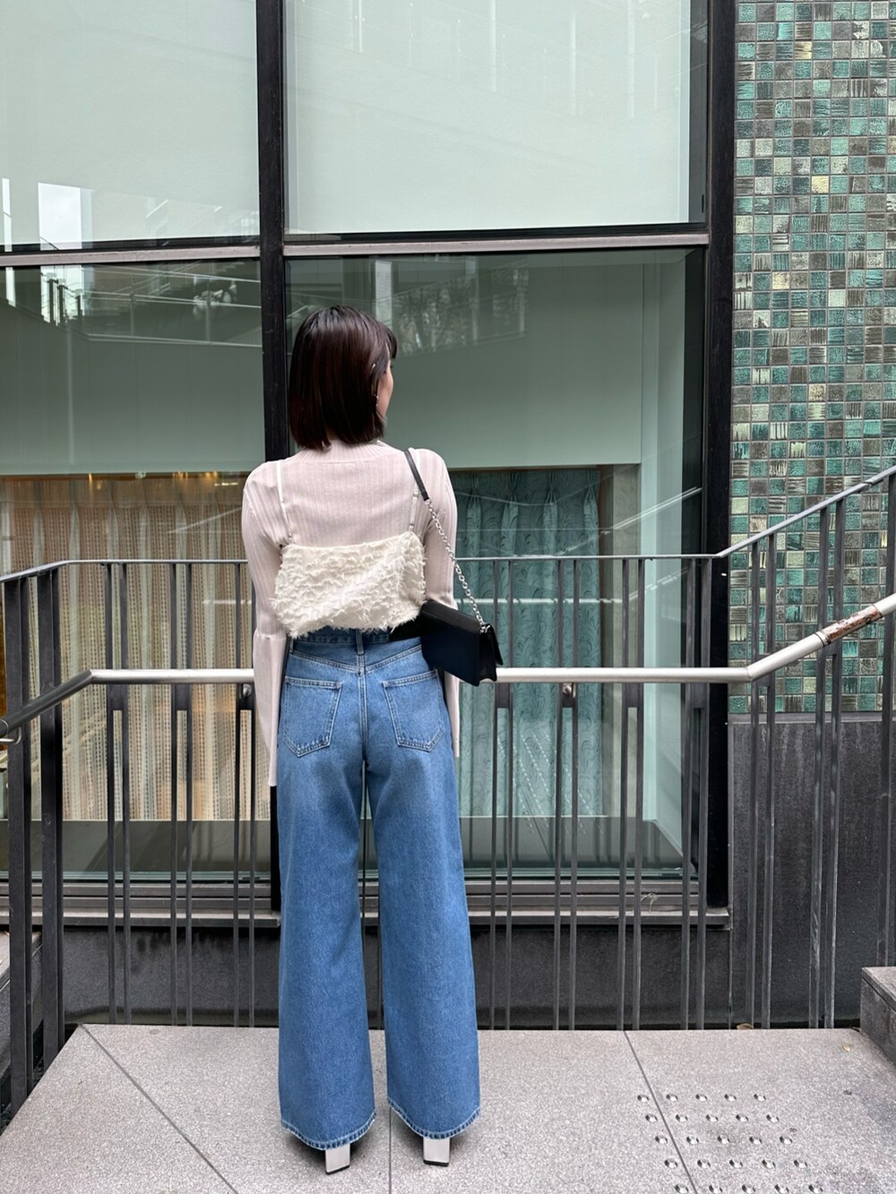 ブルー系のデニムパンツ、ホワイト系のキャミソール、ホワイト系のニット/セーターを着用したレディースの冬コーディネートの6枚目の写真