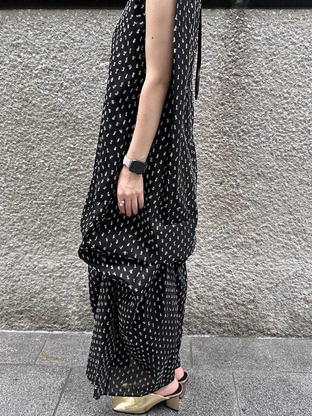 ブラック系のワンピース、ゴールド系のハンドバッグ、ゴールド系のパンプスを着用したレディースの夏コーディネートの9枚目の写真