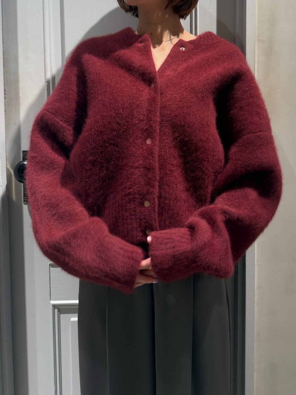 レッド系のカーディガン/ボレロ、グレー系のその他パンツ、ブラック系のローファーを着用したレディースの冬コーディネートの4枚目の写真