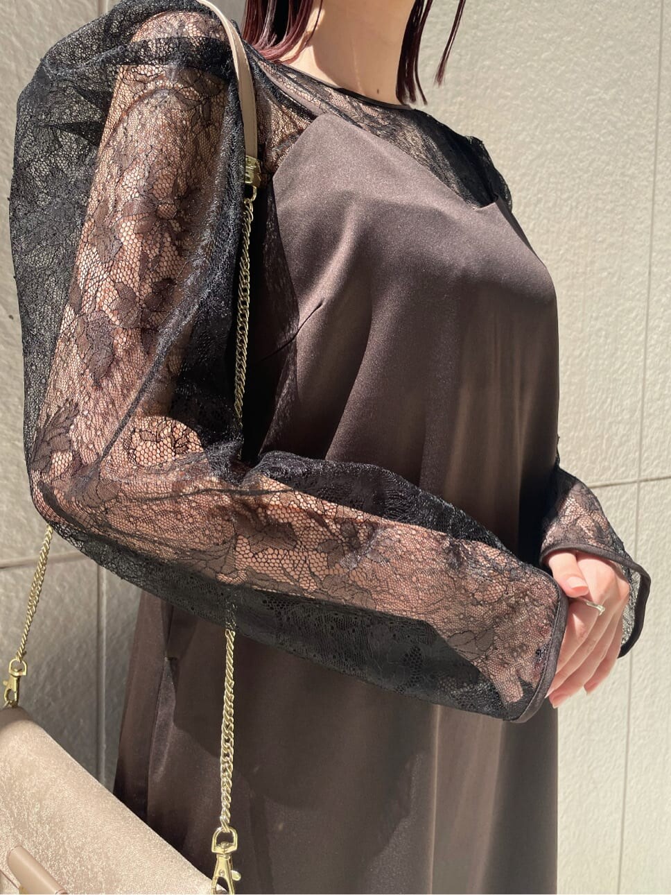 ブラック系のドレス、ベージュ系のパンプス、ベージュ系のクラッチバッグを着用したレディースの秋コーディネートの3枚目の写真