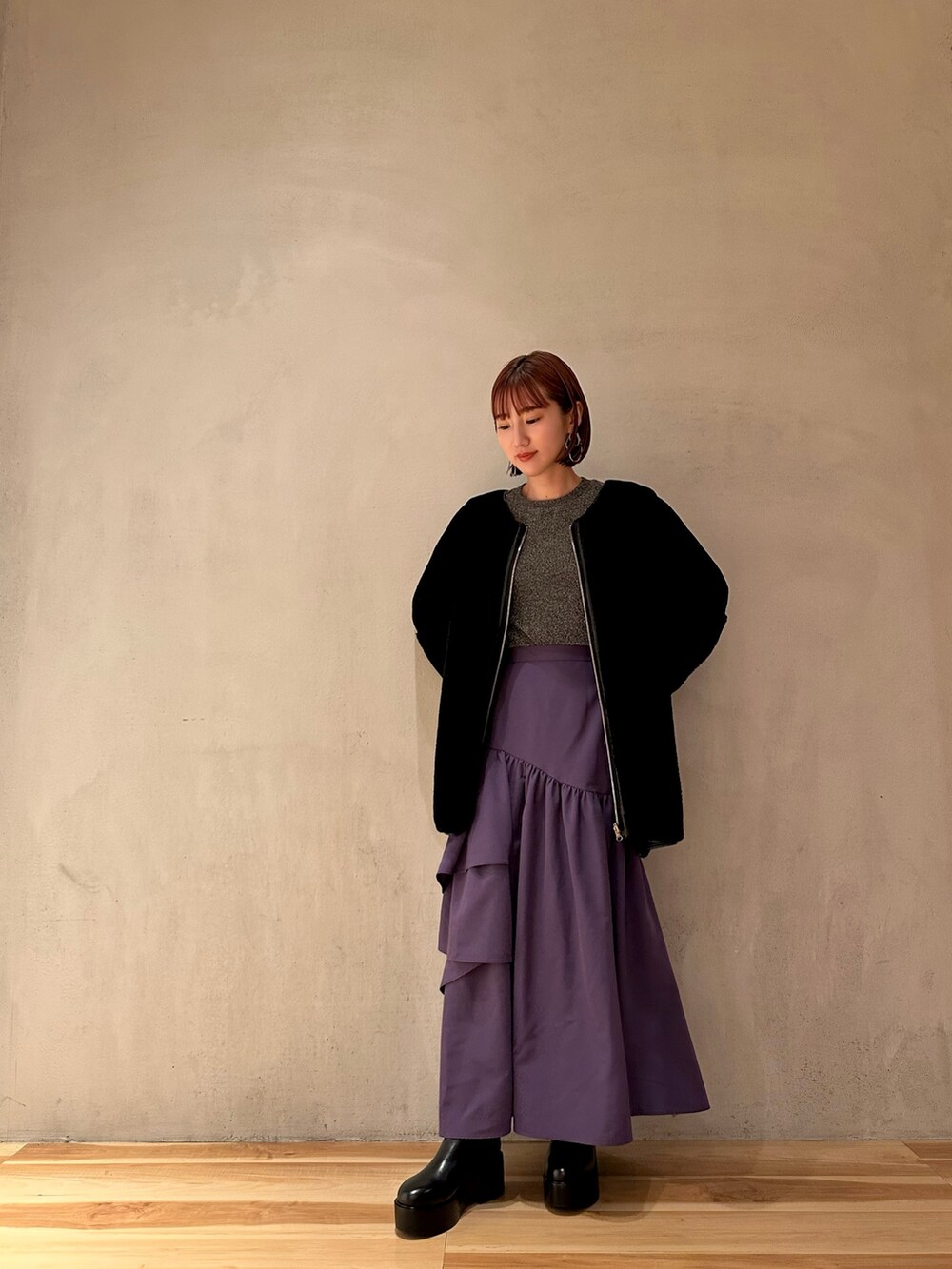 パープル系のスカート、ブラック系のノーカラーコート、シルバー系のTシャツ/カットソーを着用したレディースの秋コーディネートの2枚目の写真