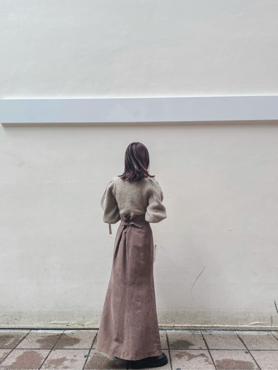 ブラック系のブーツ、ブラウン系のスカート、ベージュ系のニット/セーターを着用したレディースの秋コーディネートの4枚目の写真