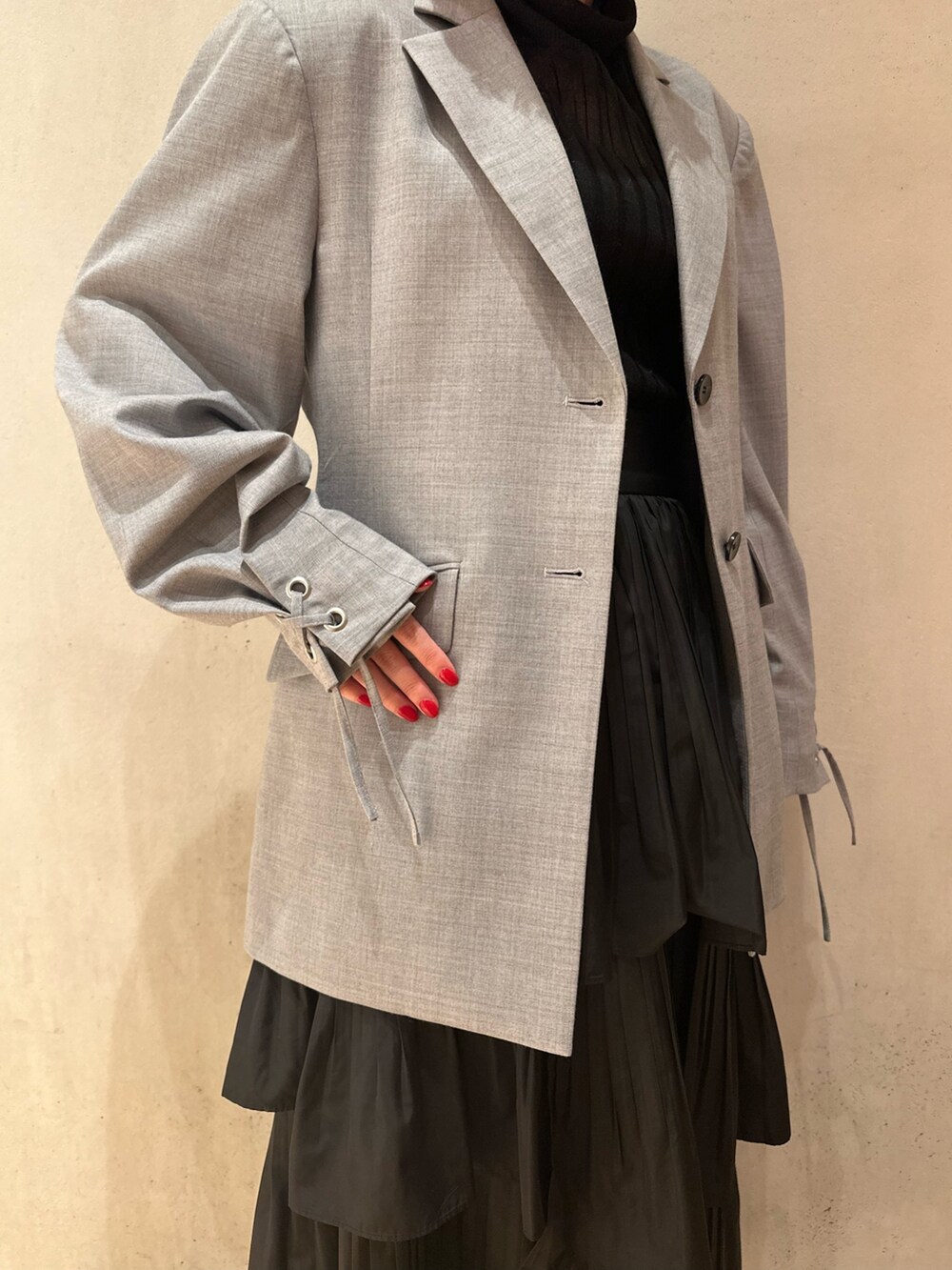 ブラック系のスカート、ブラック系のニット/セーター、グレー系のテーラードジャケットを着用したレディースの秋コーディネートの6枚目の写真