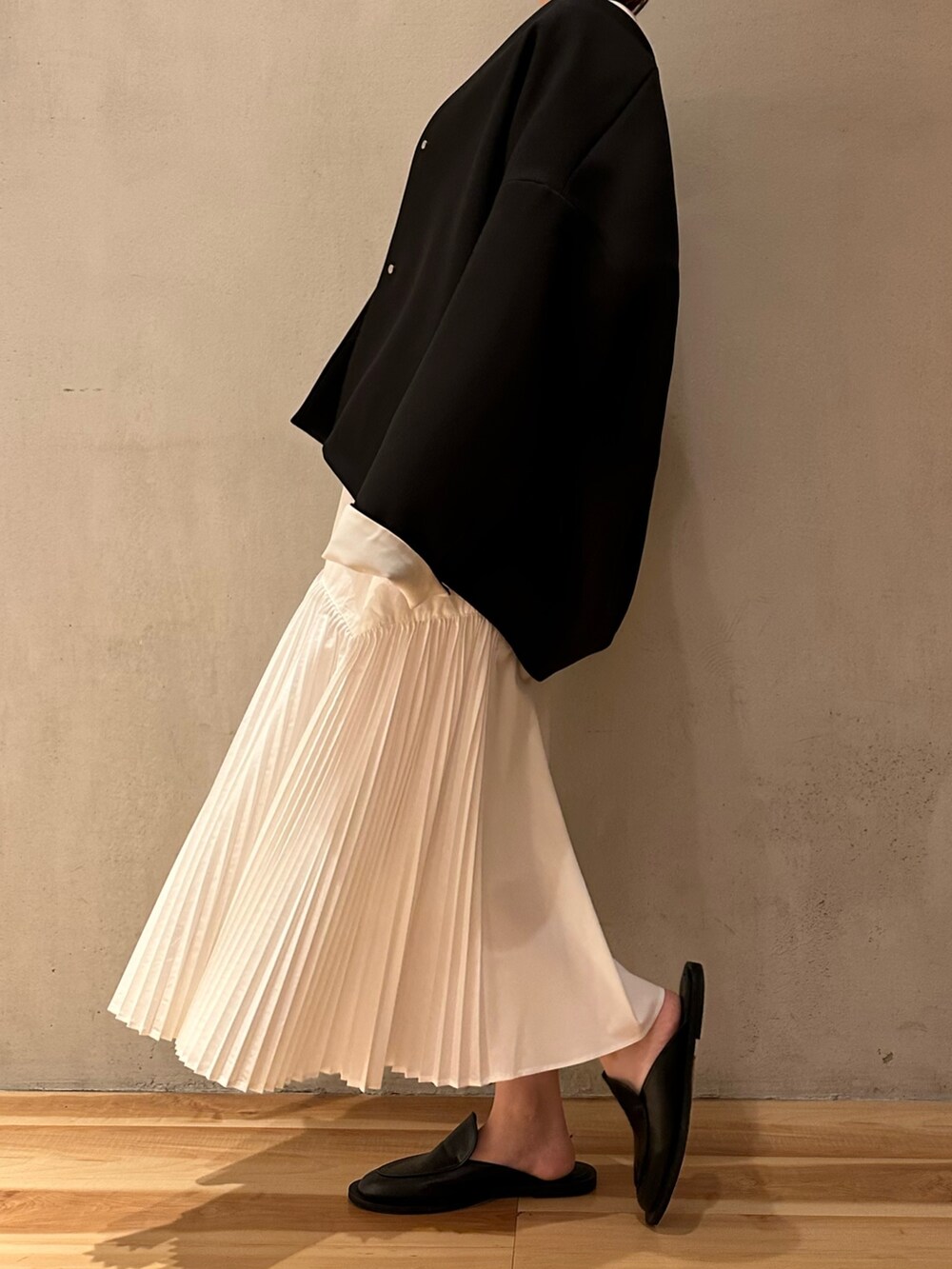 ホワイト系のワンピース、ブラック系のノーカラーコートを着用したレディースの春コーディネートの6枚目の写真