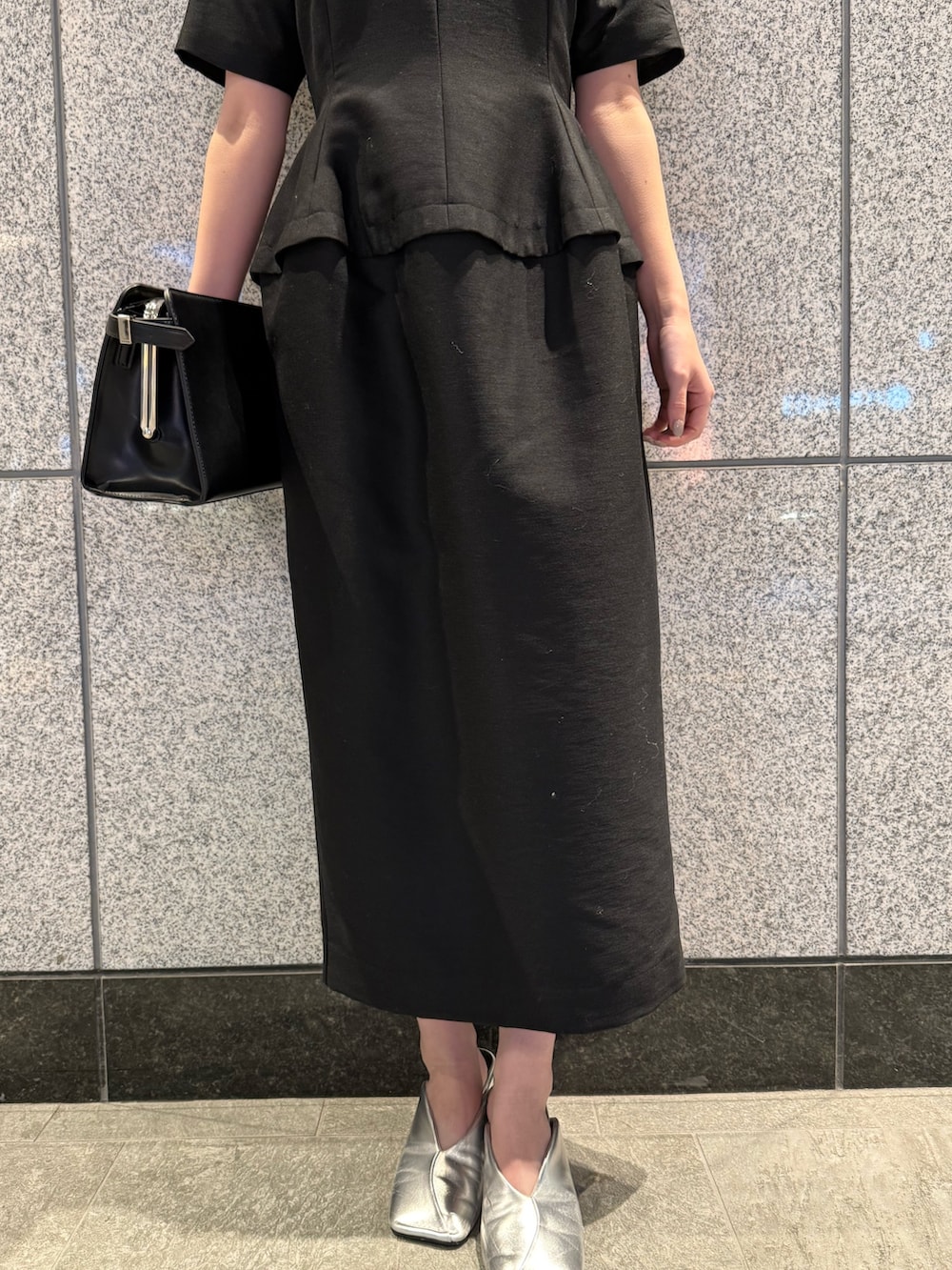 ブラック系のワンピース、ブラック系のハンドバッグを着用したレディースの冬コーディネートの7枚目の写真