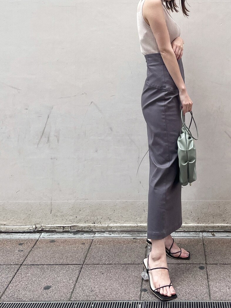 グリーン系のハンドバッグ、グレー系のスカート、ブラック系のサンダルを着用したレディースの春コーディネートの2枚目の写真
