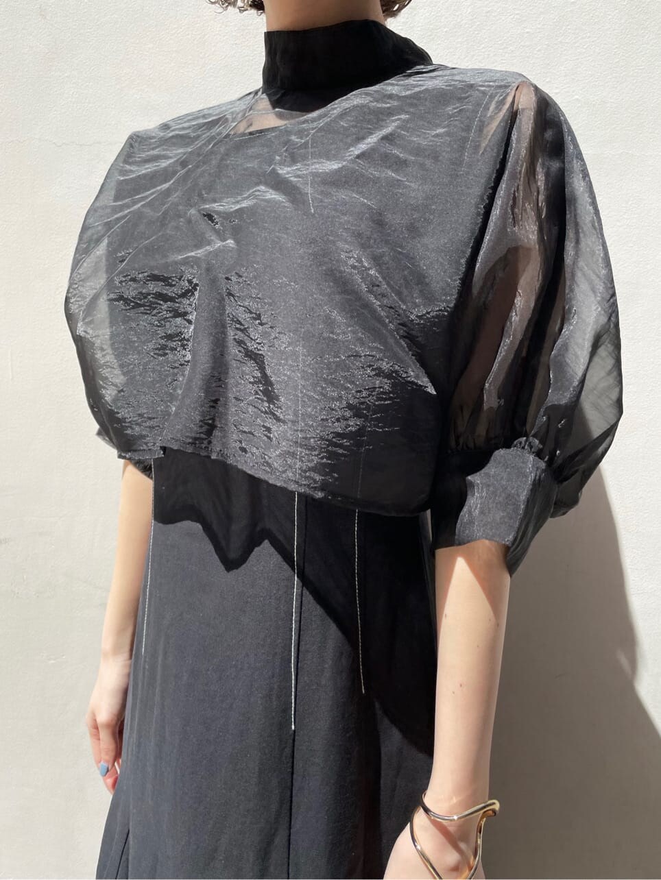 ブラウン系のパンプス、ブラック系のワンピース、ゴールド系のブレスレットを着用したレディースの春コーディネートの3枚目の写真