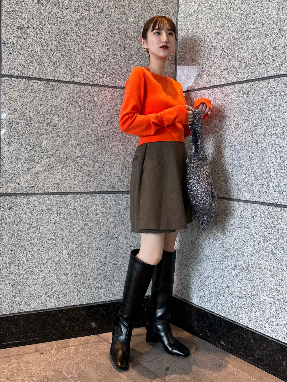 オレンジ系のニット/セーター、ブラウン系のテーラードジャケット、ブラウン系のスカートを着用したレディースの秋コーディネートの4枚目の写真