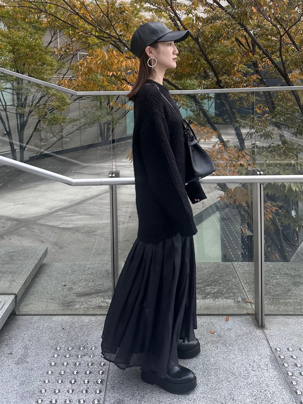 ブラック系のワンピース、ブラック系のショルダーバッグ、ブラック系のキャップを着用したレディースの秋コーディネートの4枚目の写真
