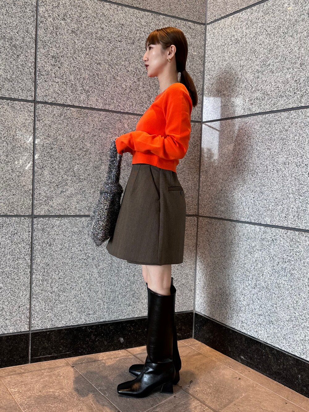 オレンジ系のニット/セーター、ブラウン系のテーラードジャケット、ブラウン系のスカートを着用したレディースの秋コーディネートの5枚目の写真