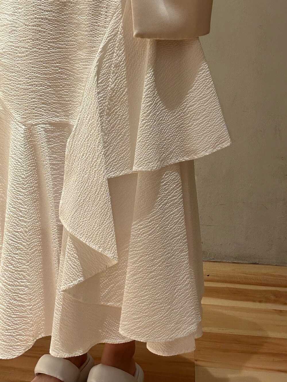 ブラウン系のノーカラーコート、ホワイト系のスカート、ホワイト系のサンダルを着用したレディースの春コーディネートの9枚目の写真