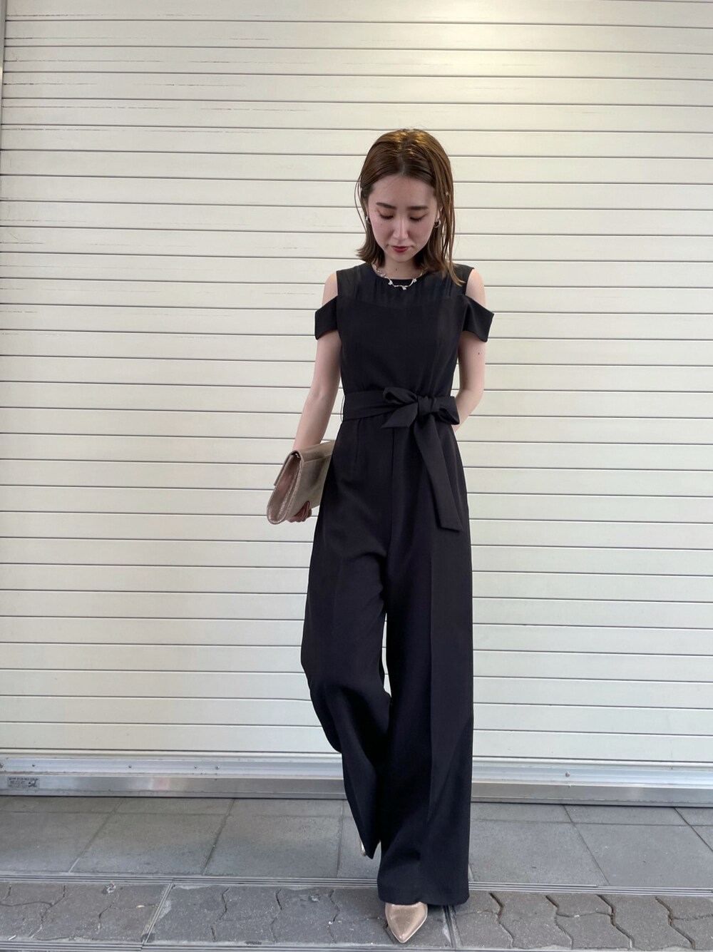 ブラック系のパンツドレス、ゴールド系のネックレスを着用したレディースの春コーディネートの2枚目の写真