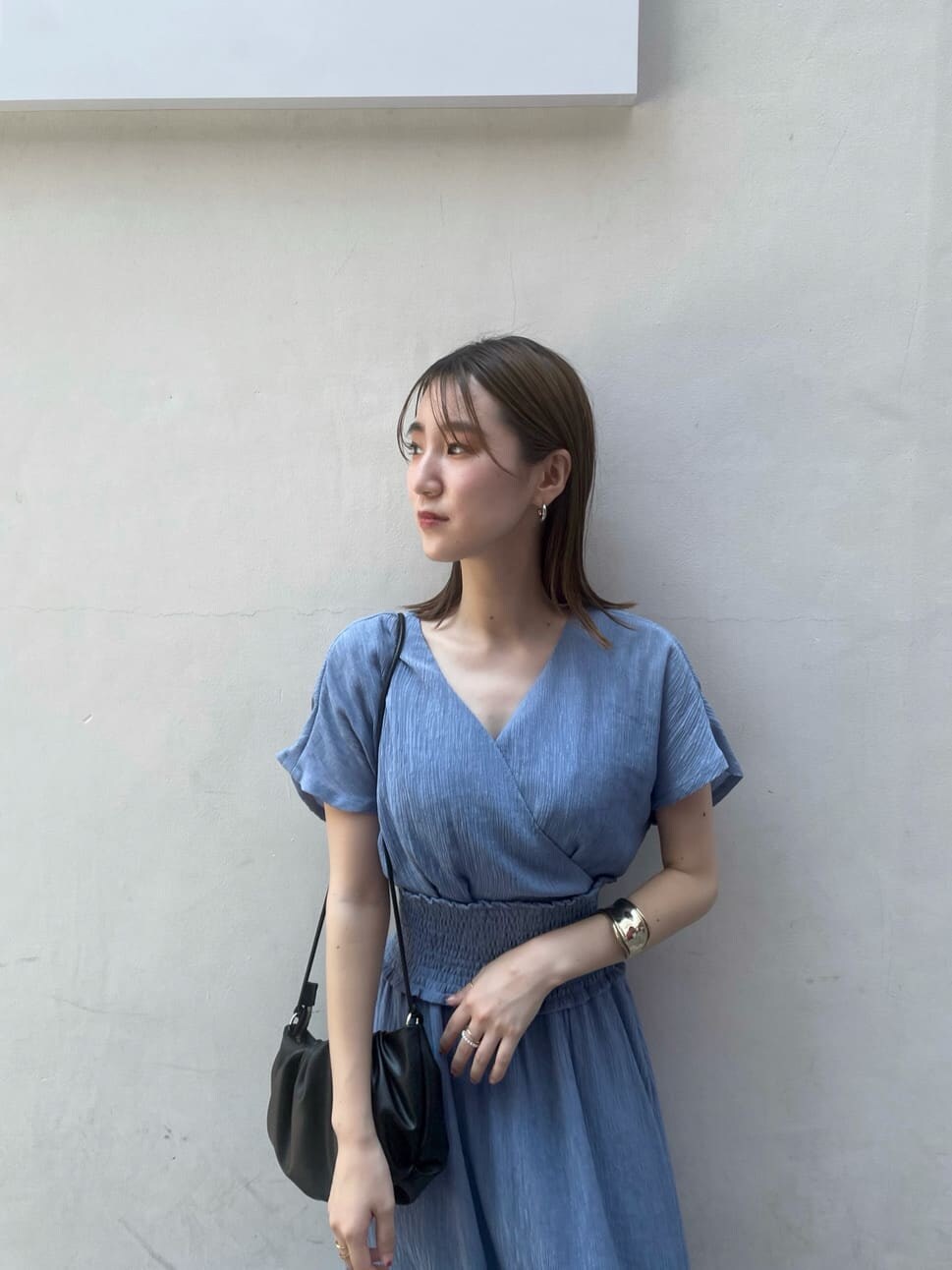 ブラック系のハンドバッグ、ブラック系のサンダル、ブルー系のワンピースを着用したレディースの夏コーディネートの3枚目の写真