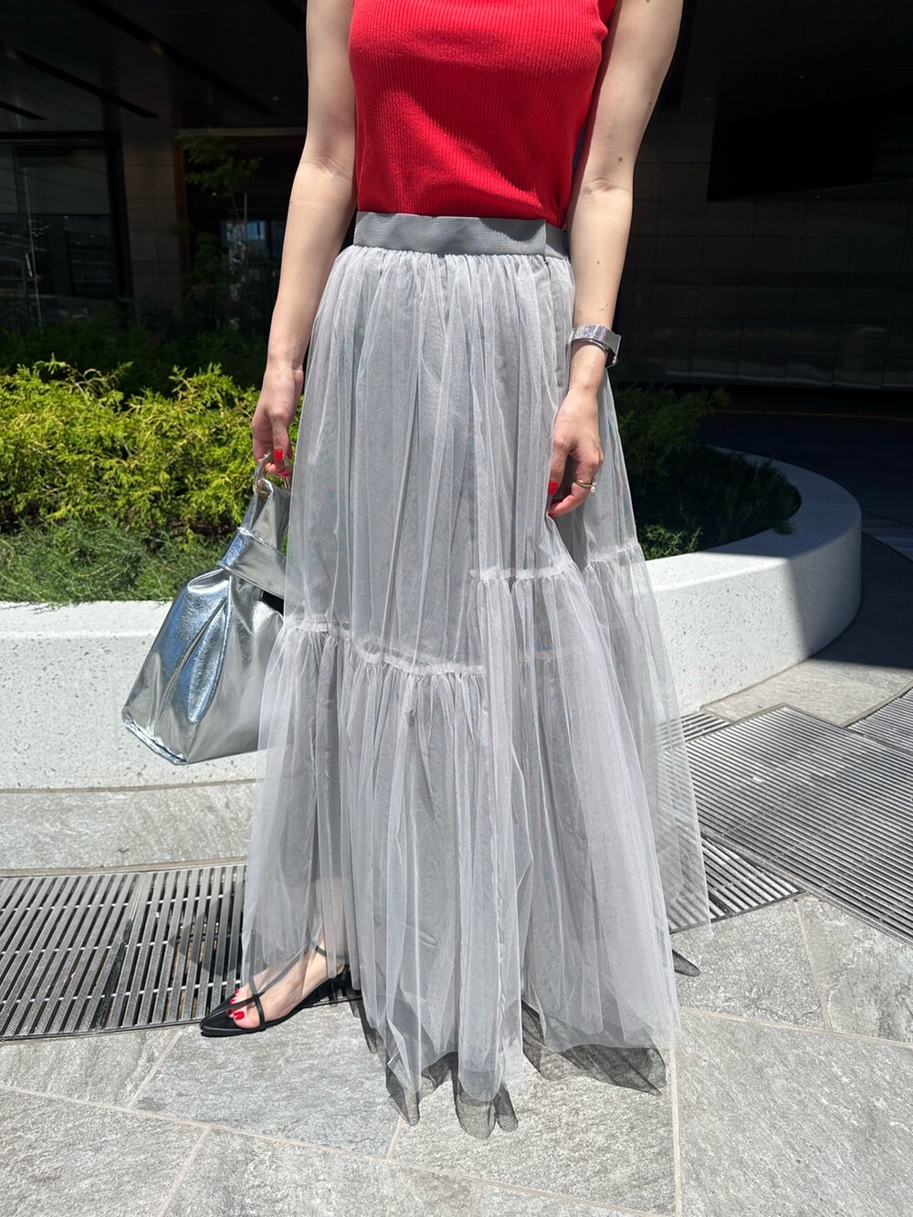 レッド系のタンクトップ、グレー系のスカートを着用したレディースの夏コーディネートの6枚目の写真