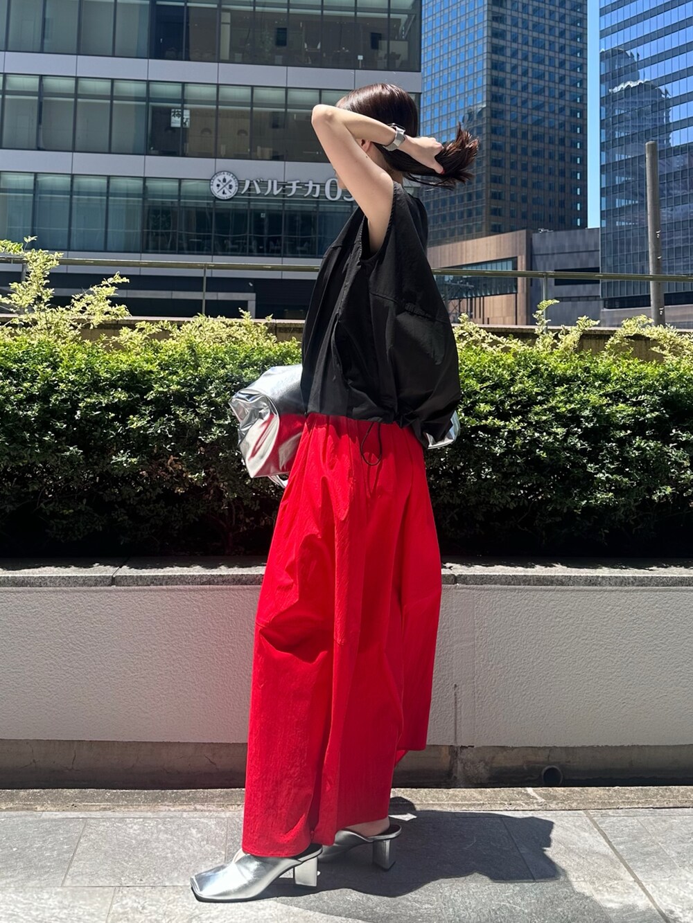 レッド系のスカート、シルバー系のパンプス、シルバー系のトートバッグを着用したレディースの夏コーディネートの3枚目の写真