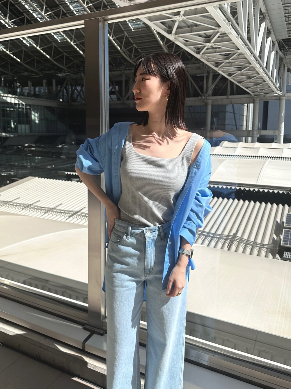 ブルー系のデニムパンツ、シルバー系のパンプス、グレー系のタンクトップを着用したレディースの春コーディネートの3枚目の写真