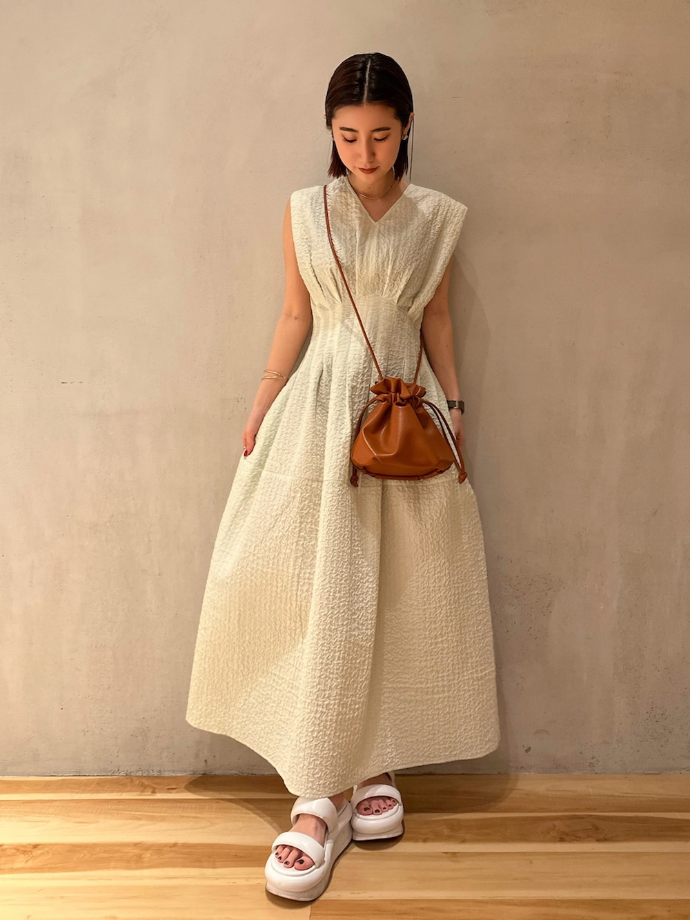 ベージュ系のテーラードジャケット、グリーン系のワンピース、ホワイト系のサンダルを着用したレディースの冬コーディネートの4枚目の写真