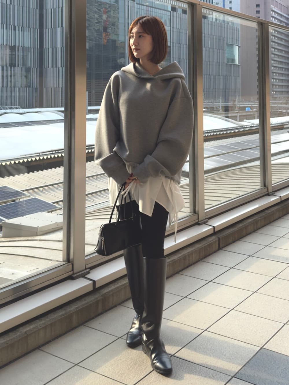 グレー系のパーカー、ブラック系のボストンバッグを着用したレディースの冬コーディネートの2枚目の写真