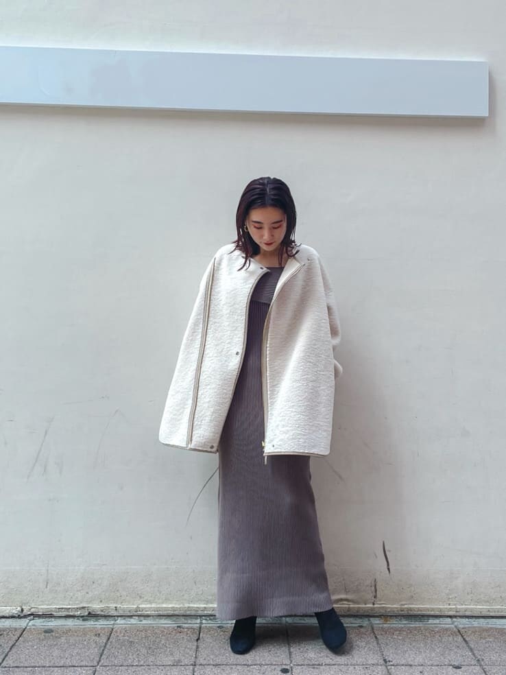 ブラック系のブーツ、ホワイト系のその他アウター、ベージュ系のワンピースを着用したレディースの秋コーディネートの6枚目の写真