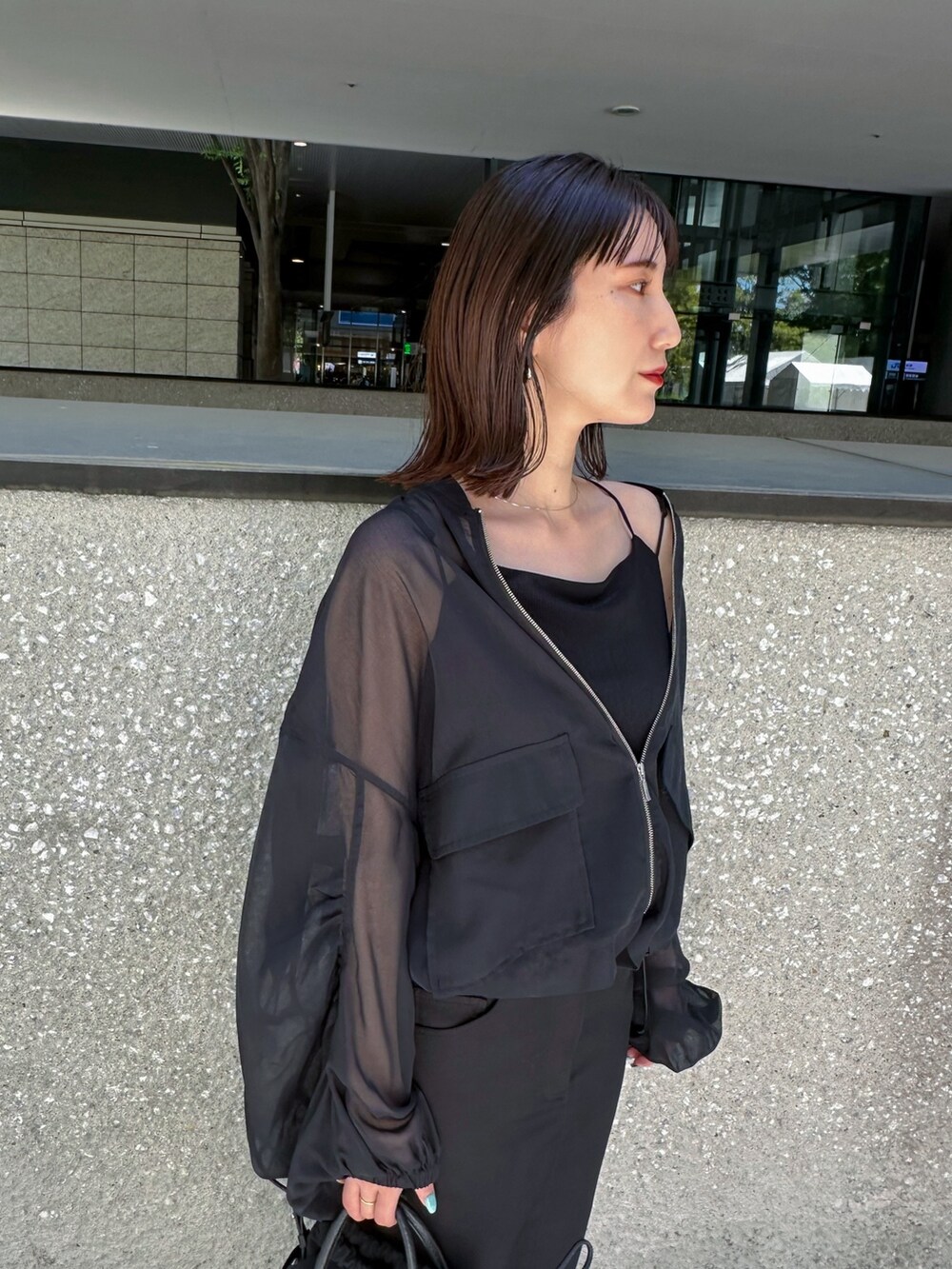ブラック系のキャミソール、ブラック系のノーカラージャケット、シルバー系のパンプスを着用したレディースの春コーディネートの5枚目の写真