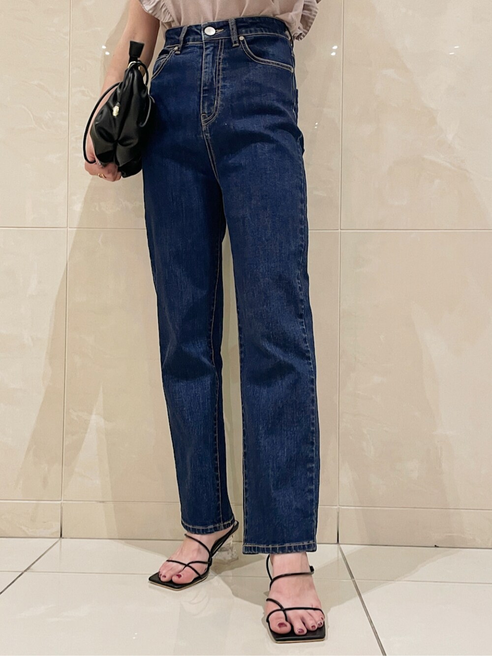 ブルー系のデニムパンツ、ブラック系のハンドバッグ、ブラック系のサンダルを着用したレディースの春コーディネートの4枚目の写真