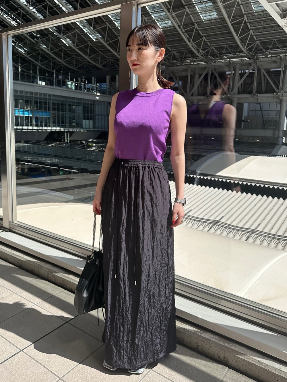 パープル系のニット/セーター、ブルー系のスカート、シルバー系のパンプスを着用したレディースの春コーディネートの3枚目の写真