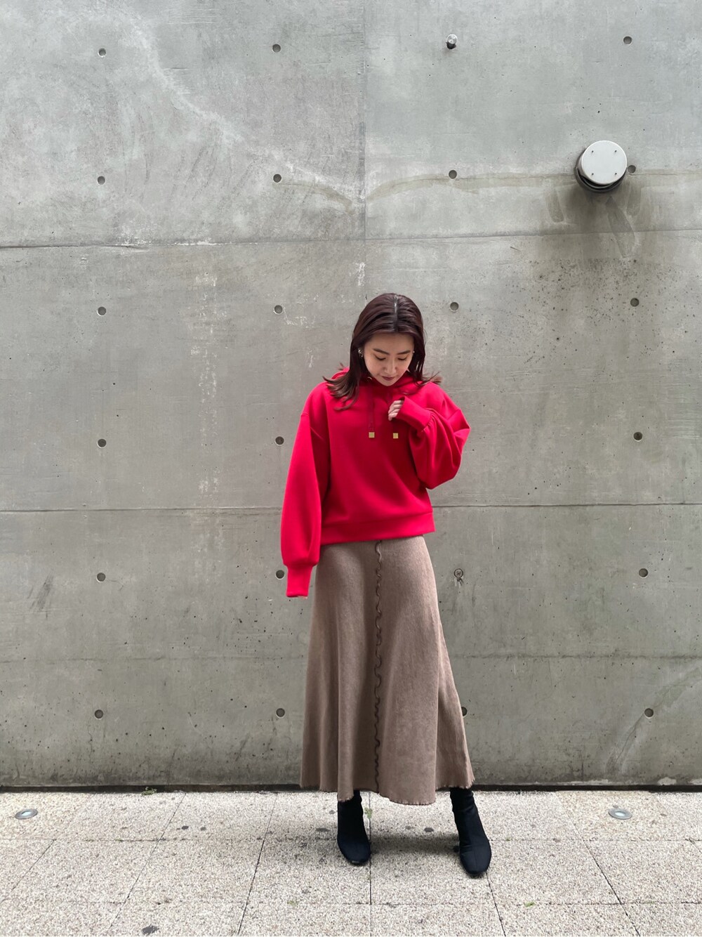 ベージュ系のワンピース、レッド系のパーカーを着用したレディースの冬コーディネートの2枚目の写真