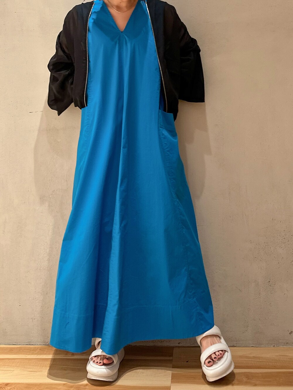 ブルー系のワンピース、ホワイト系のサンダル、ブラック系のブルゾンを着用したレディースの冬コーディネートの5枚目の写真